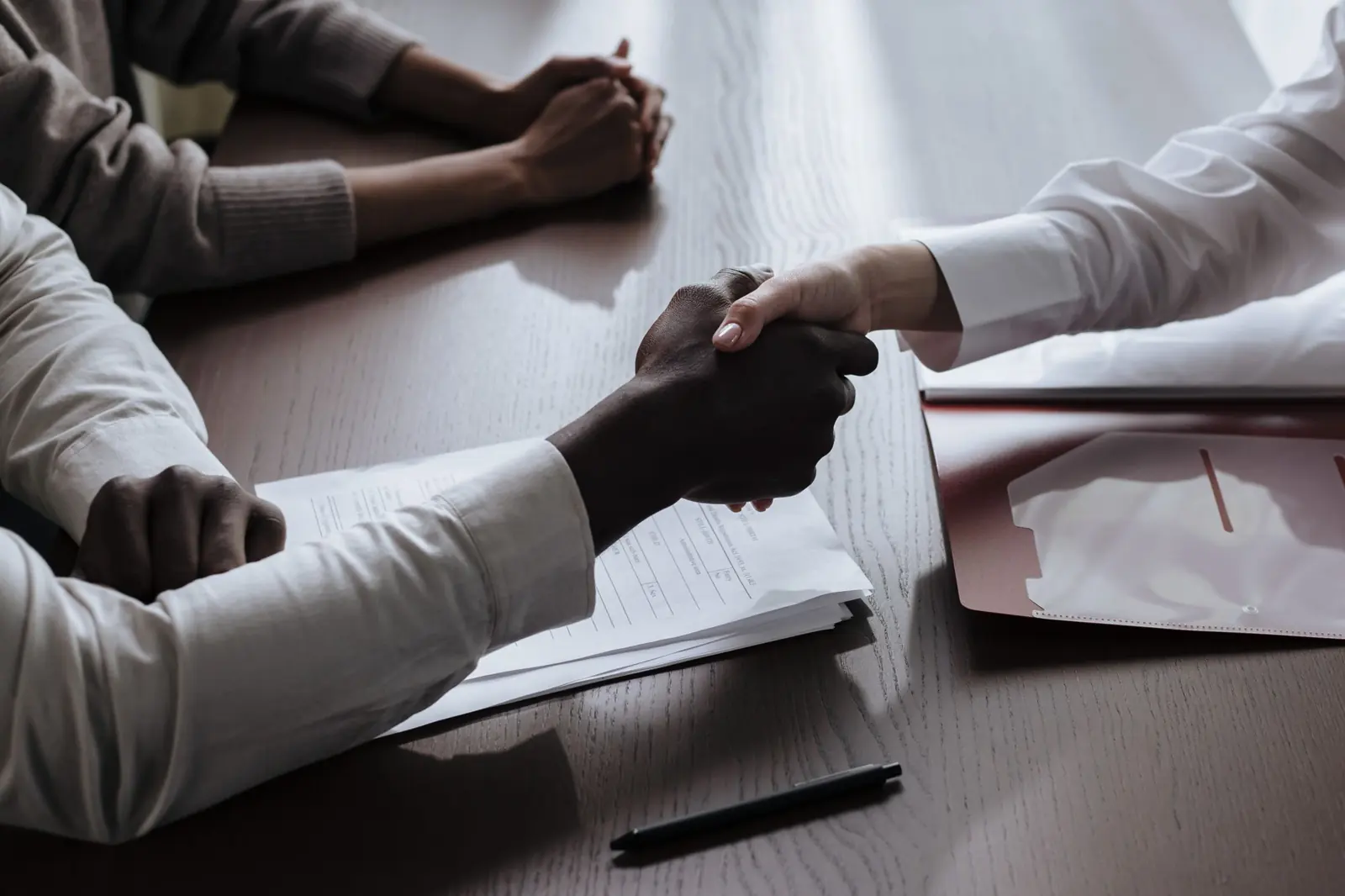 Handschlag über Unterlagen am Tisch