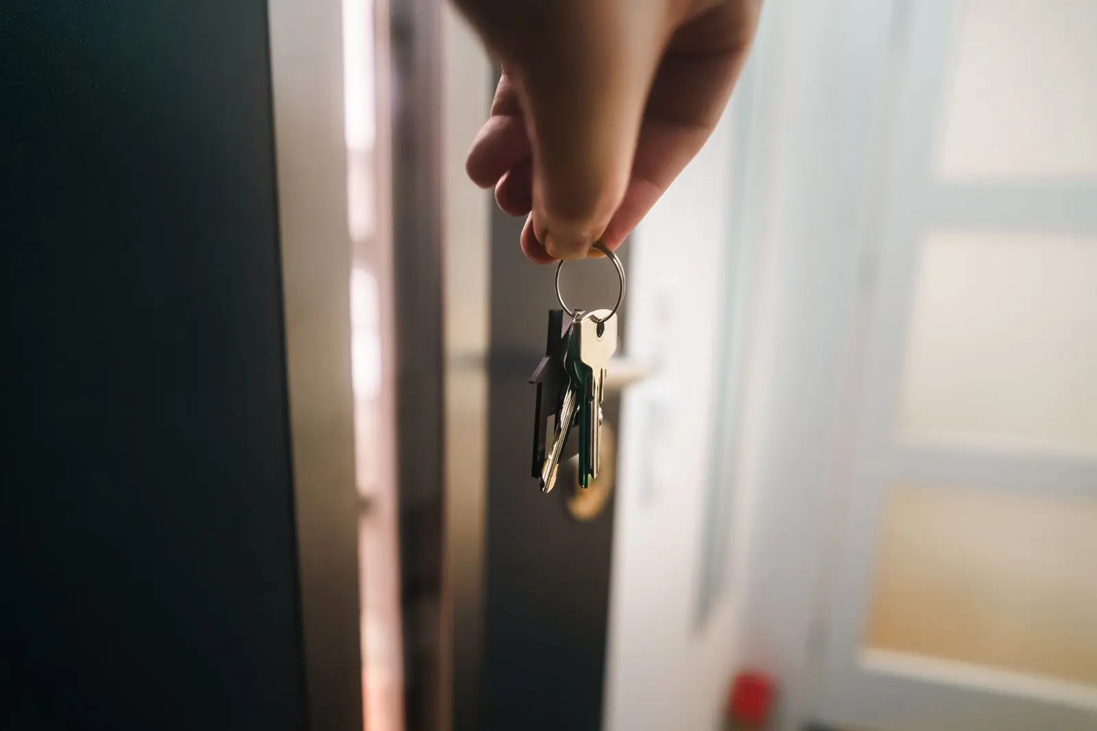 Eine Hand hält einen Wohnungsschlüssel an der geöffneten Tür