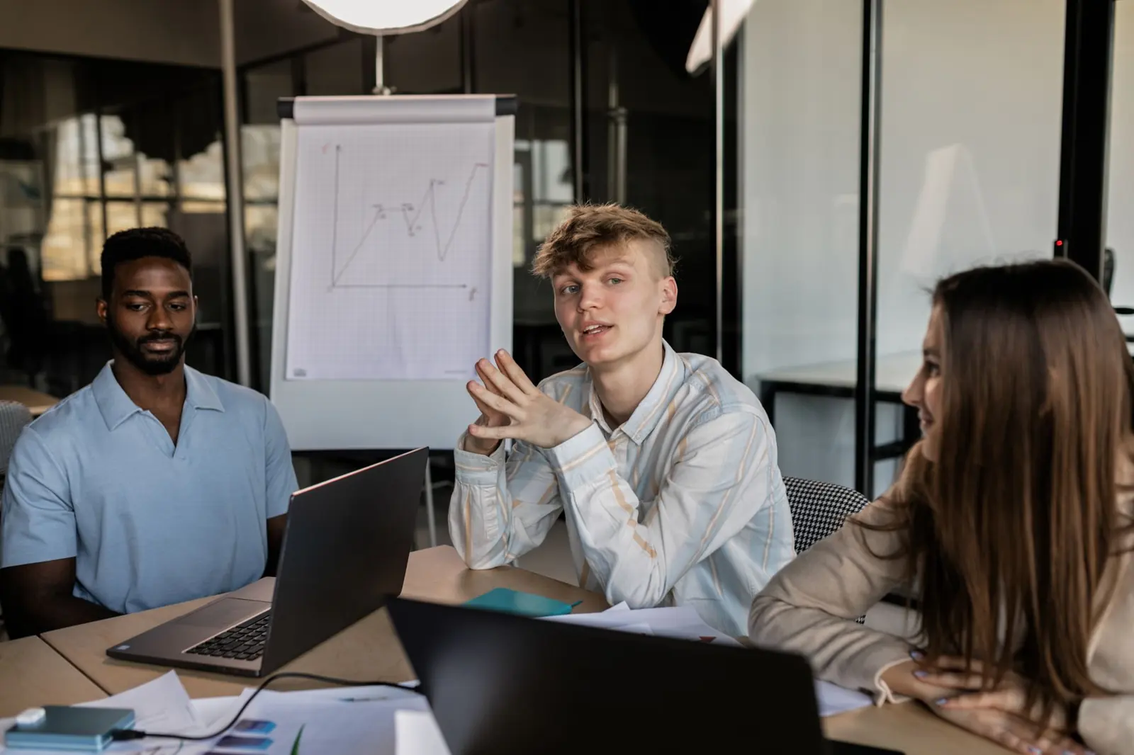 Drei Kolleginnen und Kollegen diskutieren an einem hellen Bürotisch