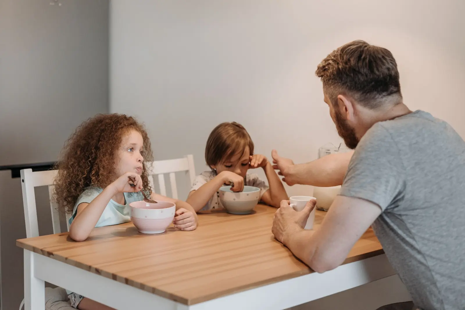 Ein Vater sitzt mit seinen Kindern am Frühstückstisch